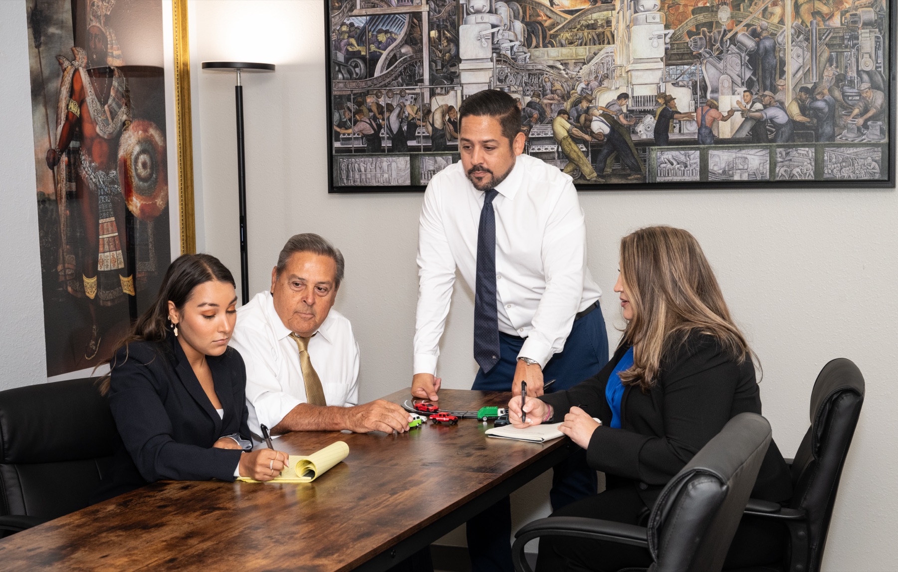 Daniel M. Gonzales at an office meeting with model vehicles on a conference table